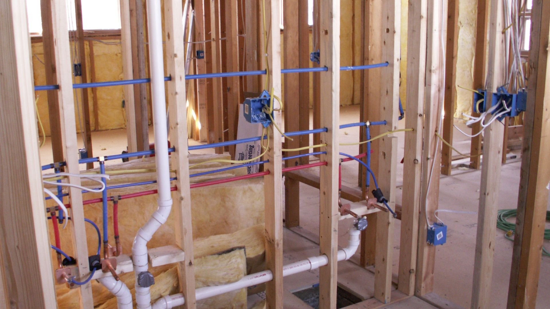 Plumbing and electrical rough-in during home construction with exposed pipes