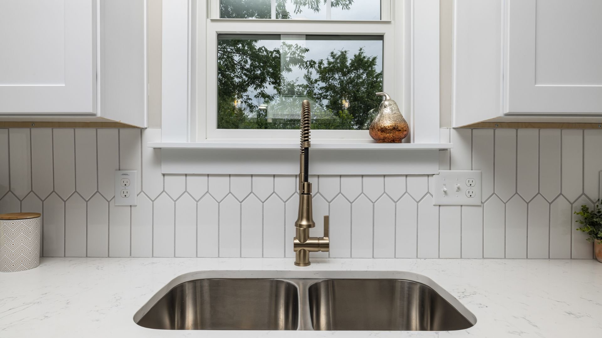 Modern kitchen sink with bronze faucet and white geometric tile backsplash